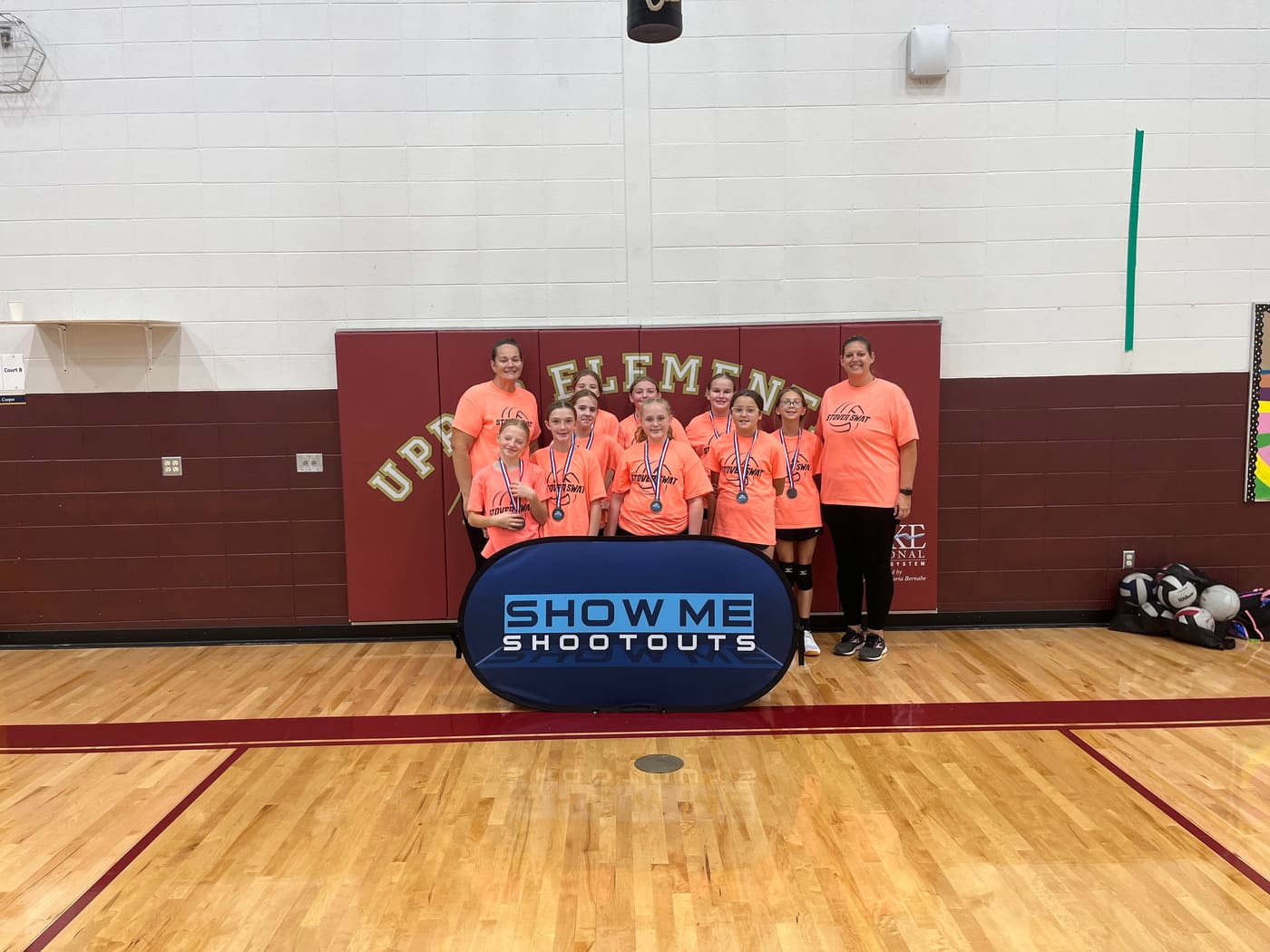 The Stover Swat team in bright orange shirts poses with their coaches and medals.